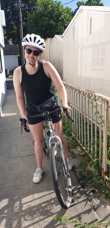 A woman about to go on a fundraising bike ride with a white helmet and silver bike.